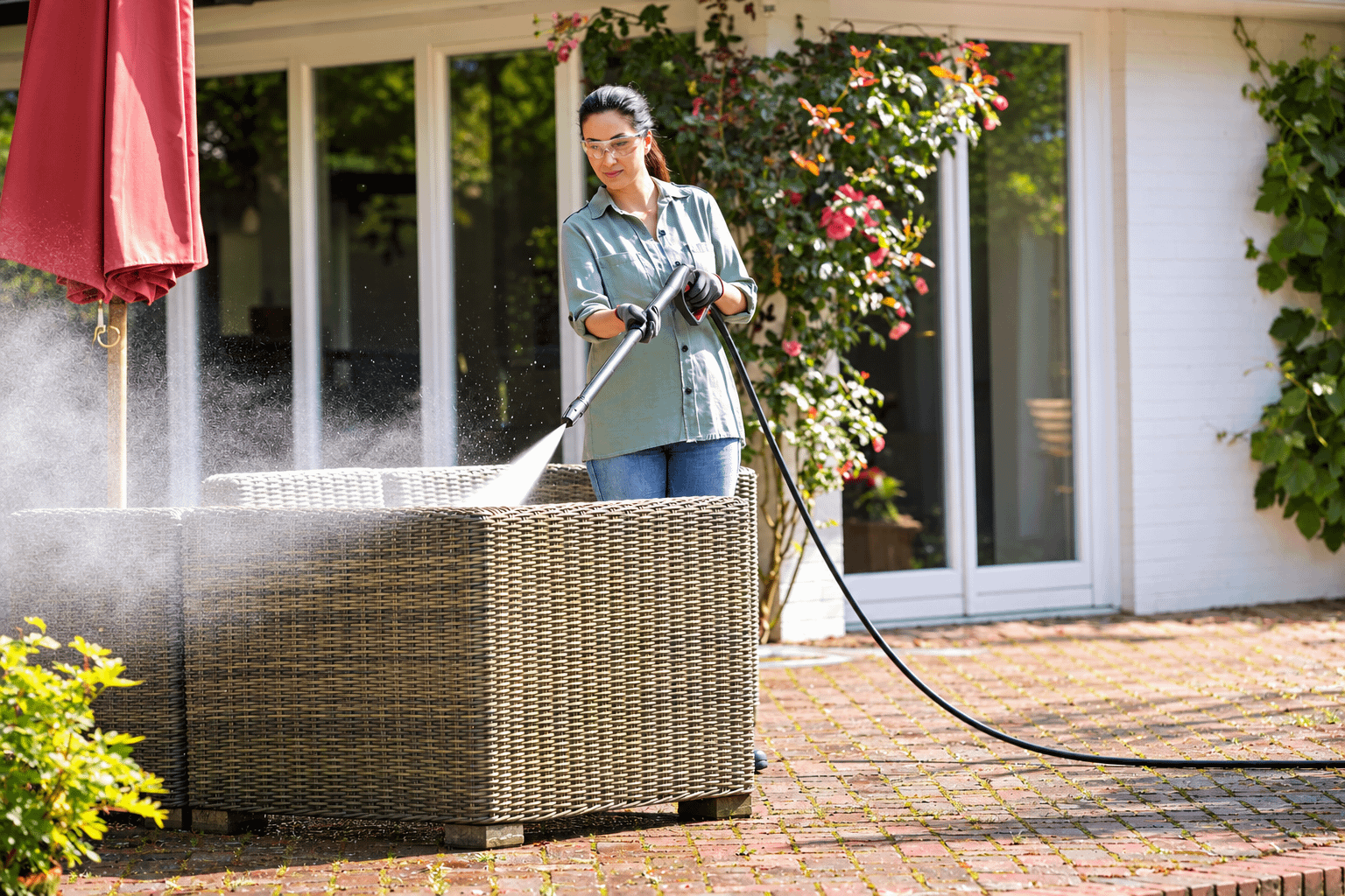 Outdoor wicker furniture being cleaned on a brick patio
